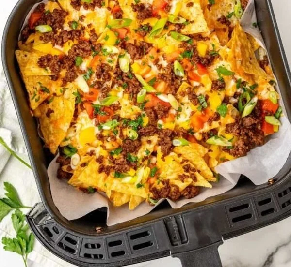 Plate of crispy Air Fryer Nachos topped with melted cheese and fresh toppings.