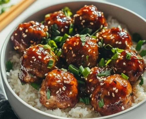 Plate of flavorful Asian meatballs garnished with herbs and sesame seeds