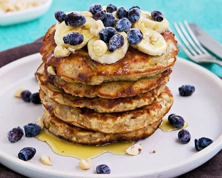 Delicious banana oatmeal pancakes stacked on a plate with syrup and fruit