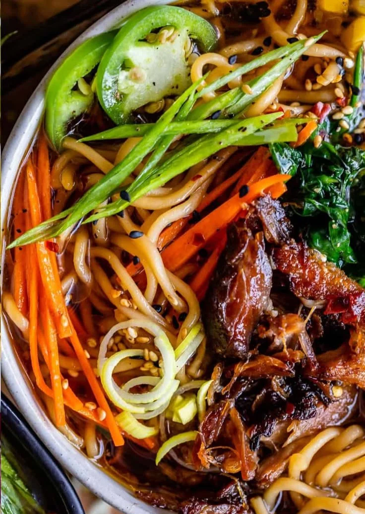 Slow cooker pork ramen garnished with green onions and soft-boiled eggs