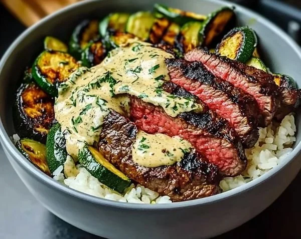Delicious grilled steak bowl with sauce and grilled zucchini on a plate.