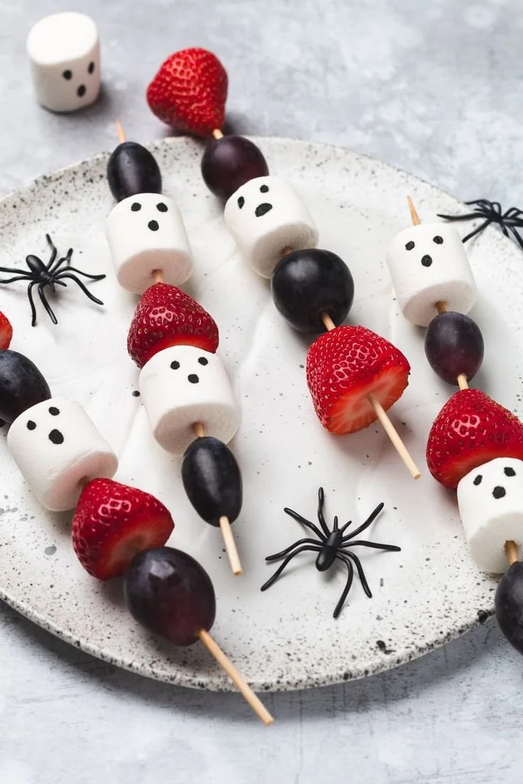 Colorful Halloween fruit skewers with spooky decorations and healthy fruit options.